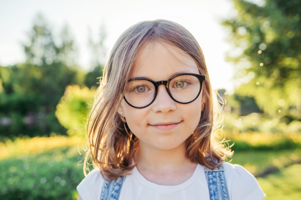 young girl outside smiling and wearing glasses